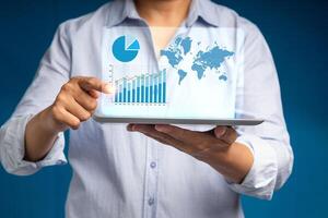 A businessman's showing a growing virtual hologram report on the tablet while standing on a blue background photo