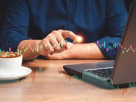 Businessman pointing on graph stock on virtual screen while sitting on the table in the office photo
