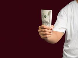 Man in a white casual holding US banknotes while standing on a red background photo