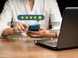 Close-up of hands woman using a smartphone gives the five-star icon a rating of very impressed for service while sitting in the office photo