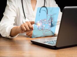 Hand of a doctor touching an image of a colon symbol on a virtual screen while sitting in the hospital photo