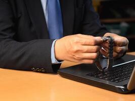 Close-up of a businessman setting a clock on a wristwatch while sitting in the office photo
