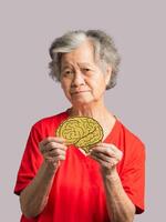 Portrait of a senior woman holding a brain symbol while standing on a gray background photo