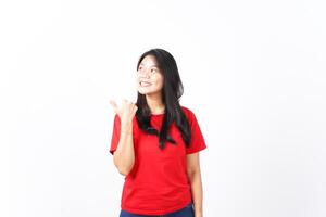 Smiling while Showing and Pointing Product With Thumb Of Beautiful Asian Woman wearing red shirt Isolated On White Background photo
