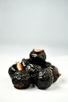 Pile of black or dark brown colored soap berry nuts or buah lerak isolated on vertical copy spaced white background. photo
