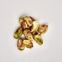 Pile of pistachio nuts without shells isolated on square white background from top view angle. photo