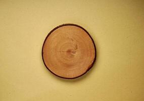 One piece of empty copy spaced sliced wood coaster isolated on horizontal brown kraft paper from top angle view. photo