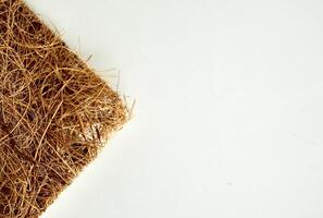 Brown scrubber tool from coconut heap textures isolated on horizontal empty copy spaced white background. photo