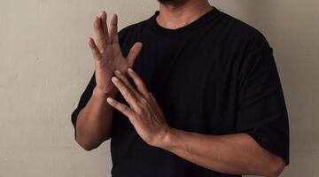 Young man showing two handed sing language gesture photo