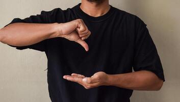 Sign Language man interpreter gesturing in sign language on gray background photo