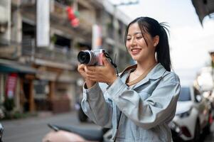 A happy Asian female tourist enjoying taking photos with her camera while exploring the city.