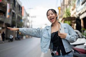 A cheerful Asian female tourist standing by the street, catching a taxi. photo