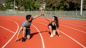 Two runners give high five while getting ready to run on a running track, training at a stadium photo