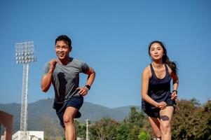 Two determined Asian athletes running on a track in a stadium on a sunny day. photo