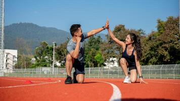 Two runners give high five while getting ready to run on a running track, training at a stadium photo