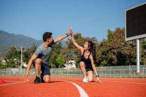 Two runners give high five while getting ready to run on a running track, training at a stadium photo
