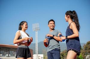 A group of Asian athlete runners enjoy a conversation while resting on a running track at a stadium. photo