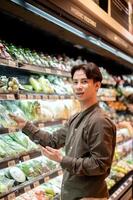 A man selecting vegetables from a shelf while grocery shopping at a supermarket or grocery store. photo