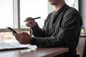 A close-up of an Asian businessman using his smartphone while working in a modern office. photo