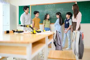 Portrait of a teacher and kids in a classroom where children have pleasure learning photo