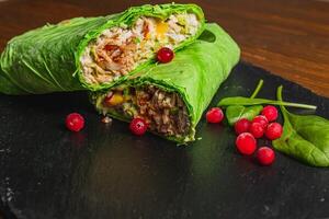 Homemade shawarma with spinach filled with chicken, vegetables and cranberries photo