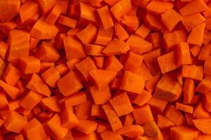 Fresh carrots cut into small cubes as a background for a vegan concept photo