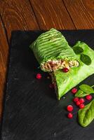 Homemade shawarma with spinach filled with chicken, vegetables on a stone board photo