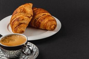 Freshly Baked Croissants and a Cup of Espresso on a Beautiful Dark Background photo