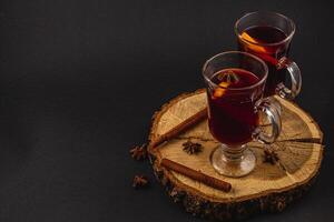 aromatic mulled wine with spices on a piece of wood on a black background photo