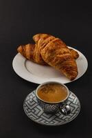 Freshly Baked Croissants and a Cup of Espresso on a Beautiful Dark Background photo