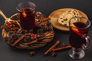 aromatic mulled wine with fresh stollen on a wooden plate on a black background photo