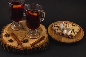 aromatic mulled wine with fresh stollen on a wooden plate on a black background photo