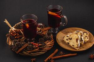 aromatic mulled wine with fresh stollen on a wooden plate on a black background photo