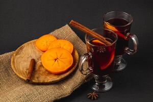 Festive Christmas mulled wine with sweet persimmons on a black background photo