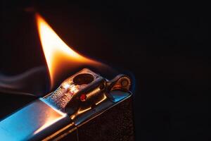 Janalyso Lighting a Zippo Close-Up on Dark Black Background. Concept of Handheld Firestarters, Vintage Collectibles, and Urban Aesthetics photo