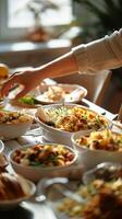Close-up of a hand reaching for a dish at a festive dining table with a variety of food. Concept of family gatherings, holiday meals, celebration, sharing food. Vertical photo