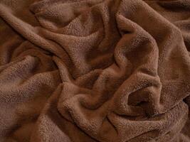 Close-up of soft brown fleece fabric with folds and texture. Concept of cozy materials, warmth, comfort, and textile design. Background, Texture photo