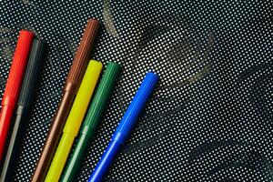 Multicolored felt tip pens markers for drawing on dark spotted fabric photo