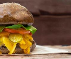 Traditional rustic burger sandwich with cheddar cheese, vegetables and Australian bread in creative photography and cozy village setting photo