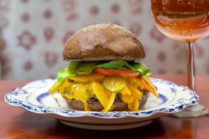 Traditional rustic burger sandwich with cheddar cheese, vegetables and Australian bread in creative photography and cozy village setting photo