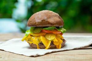 Traditional rustic burger sandwich with cheddar cheese, vegetables and Australian bread in creative photography and cozy village setting photo