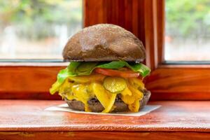 Traditional rustic burger sandwich with cheddar cheese, vegetables and Australian bread in creative photography and cozy village setting photo