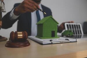 Auctioneer knocks down property sale by sample house and lawyer's gavel, judge mediates in property dispute in court car judge's gavel on wooden background Buying and selling real estate, housing photo