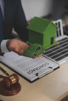 Auctioneer knocks down property sale by sample house and lawyer's gavel, judge mediates in property dispute in court car judge's gavel on wooden background Buying and selling real estate, housing photo
