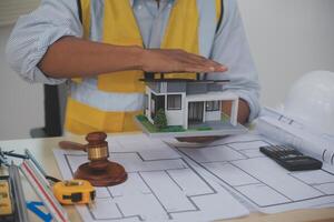 Judge gavel on building blueprint plans with a yellow safety helmet in the background. law that deals with matters relating to building construction, engineering. Construction law concept. photo