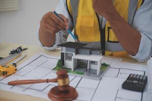 Judge gavel on building blueprint plans with a yellow safety helmet in the background. law that deals with matters relating to building construction, engineering. Construction law concept. photo
