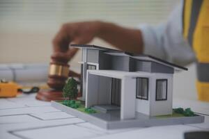Judge gavel on building blueprint plans with a yellow safety helmet in the background. law that deals with matters relating to building construction, engineering. Construction law concept. photo