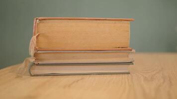 An open book with its pages gently turning rests on a wooden table in the breeze video