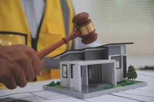 Judge gavel on building blueprint plans with a yellow safety helmet in the background. law that deals with matters relating to building construction, engineering. Construction law concept. photo