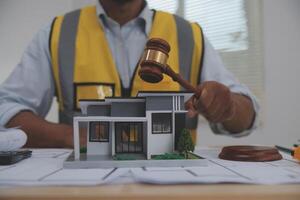 Judge gavel on building blueprint plans with a yellow safety helmet in the background. law that deals with matters relating to building construction, engineering. Construction law concept. photo
